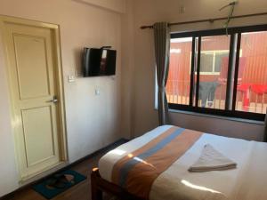 a bedroom with a bed and a window and a television at Hotel Ramanam in Kathmandu