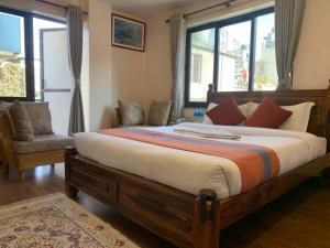 ein Schlafzimmer mit einem großen Bett, einem Stuhl und Fenstern in der Unterkunft Hotel Ramanam in Kathmandu
