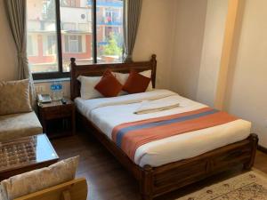 a bedroom with a bed and a couch and a window at Hotel Ramanam in Kathmandu