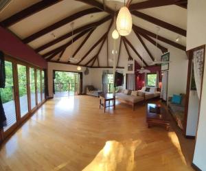 una gran sala de estar con suelo de madera y techo con vigas. en Treeverb Beach House - Daintree, en Cow Bay