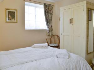 um quarto com uma cama branca com uma cadeira e uma janela em The Bothy em Staple