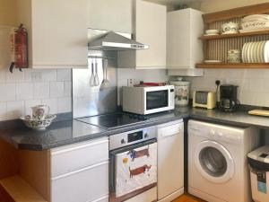 eine Küche mit einer Waschmaschine und einer Mikrowelle in der Unterkunft The Bothy in Staple