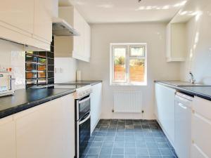 cocina con armarios blancos y suelo de baldosa azul en Irenic Lodge, en Netley