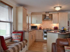 a kitchen with wooden cabinets and a couch in a room at Sunsets Spinnaker in Newquay