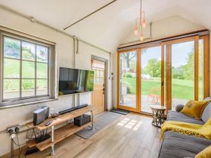 ein Wohnzimmer mit einem TV und einem Sofa in der Unterkunft The Cottage High Wykehurst End in Cranleigh