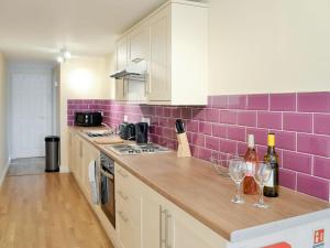 Saint Hilary的住宿－Lindum Leys，厨房的墙上铺有紫色瓷砖,配有酒杯
