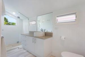 Baño blanco con lavabo y espejo en Noosa Boutique Apartments & Elkhorn Villas, en Noosa Heads