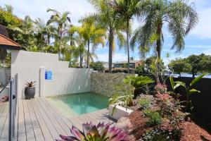 a swimming pool in a backyard with palm trees at Noosa Boutique Apartments & Elkhorn Villas in Noosa Heads