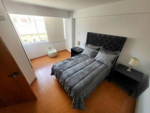 a bedroom with a bed with a headboard and two tables at Aurora Guest House - Luxury Apartment in Huaraz