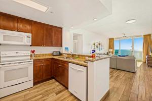 a kitchen with white appliances and a view of the ocean at AQUA RESORT! Beachfront, 3 Bedroom Condo! 2 Bedrooms Beach Front! Sleeps 7! Free Beach Chairs by Dolce Vita Getaways PCB in Panama City Beach