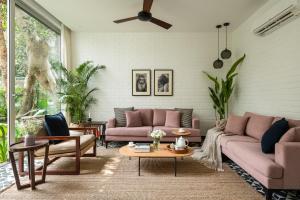 a living room with pink couches and tables at La Avila by The Blue Kite - 2 BHK Villas near Morjim Beach & Thalassa with Private Pool, Kitchen, Balcony & Security in Siolim
