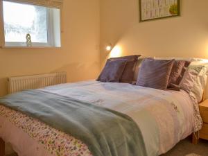 a bedroom with a bed with purple pillows and a window at Mendip in Cheddar