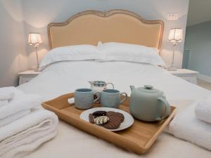 a tray with two cups and a plate of food on a bed at Woodcrest Barn Cottage - Ukc1065 in Shelfanger