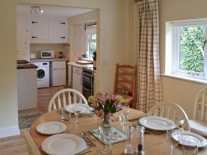 a dining room table with a vase of flowers on it at Broad Cottage Boathouse in Ranworth