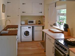 a kitchen with a washing machine and a microwave at Broad Cottage Boathouse in Ranworth
