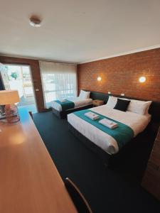 a bedroom with two beds and a brick wall at Moama Motel in Moama
