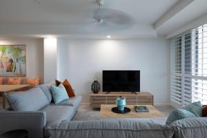 a living room with a couch and a flat screen tv at Beachfront Villa in Coolum Beach