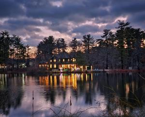 a large house sitting on top of a lake at Le Elona, a private island getaway experience in Peabody