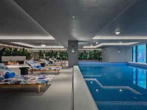 a swimming pool with lounge chairs next to a swimming pool at Hotel Indigo Hangzhou Uptown,Close to Westlake , boutique design hotel with freeflow minibar in Hangzhou