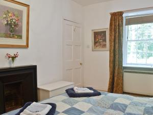 a bedroom with a bed and a fireplace and a window at Gilminscroft Gatehouse in Sorn