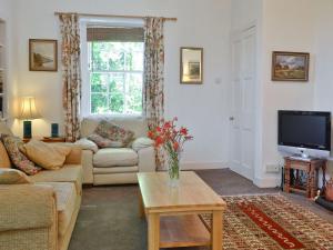 a living room with a couch and a tv at Gilminscroft Gatehouse in Sorn