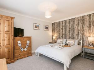 um quarto com uma cama branca e uma televisão em Amelia House em Sheringham