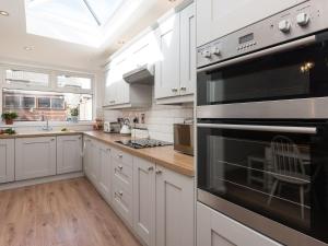 uma cozinha com armários brancos e electrodomésticos pretos em Amelia House em Sheringham