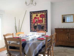 a dining room table with chairs and a painting on the wall at Maison bretonne rénovée, grand jardin, WIFI, à 5 min des plages et commerces - FR-1-368-4 in Trébeurden
