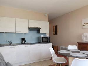 een keuken met witte kasten en een tafel bij Appartement Trégastel, 1 pièce, 3 personnes - FR-1-368-122 in Trégastel