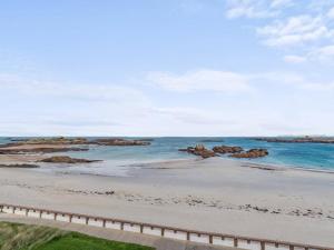 a beach with rocks in the water and a fence at Duplex 2 chambres face à la plage avec parking, au top à Trégastel - FR-1-368-204 in Trégastel
