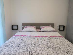 Schlafzimmer mit einem Bett mit rosa und weißer Bettwäsche und Kissen in der Unterkunft Appartement rénové 3* avec WIFI, centre-ville Perros-Guirec, proche plages et commerces - FR-1-368-263 in Perros-Guirec