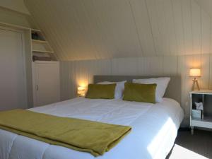 ein Schlafzimmer mit einem großen weißen Bett mit zwei grünen Kissen in der Unterkunft Maison de charme avec jardin, terrasse et WIFI, à 600m de la mer à Pleumeur-Bodou - FR-1-368-294 in Pleumeur-Bodou