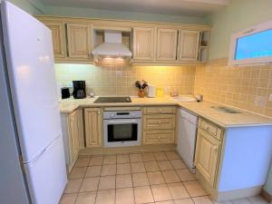 eine Küche mit Holzschränken und einem weißen Kühlschrank in der Unterkunft Maison à Perros-Guirec avec WIFI, proche centre-ville et plage, cour fermée, parking privé - FR-1-368-324 in Perros-Guirec + 2 Fotos