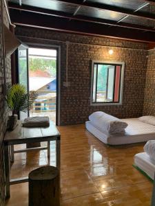 Cette chambre comprend 2 lits, une table et des fenêtres. dans l'établissement Milk Milk Homestay, à Yên Minh
