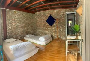 Cette chambre comprend 2 lits et un mur en briques. dans l'établissement Milk Milk Homestay, à Yên Minh