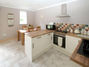 a kitchen with white cabinets and a stove top oven at Squirrels Drey in North Walsham