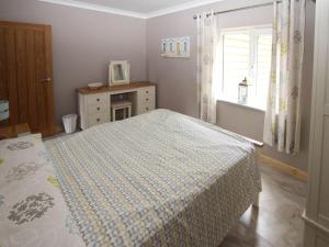 a bedroom with a bed and a dresser and a window at Squirrels Drey in North Walsham