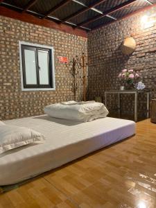- un grand lit dans une chambre dotée d'un mur en briques dans l'établissement Milk Milk Homestay, à Yên Minh