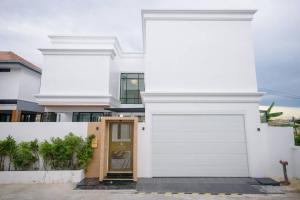 uma casa branca com uma porta de garagem branca em Pattaya Villa w/bathtub - Exquisite Pool Villa I em Nong Prue