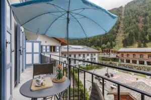 Vallorcine Apartments - Happy Rentals في فالورسين: مظلة زرقاء فوق شرفة مع طاولة