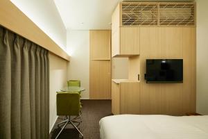京都市にあるHOTEL KYOTOLOGYのベッド1台、薄型テレビが備わるホテルルームです。