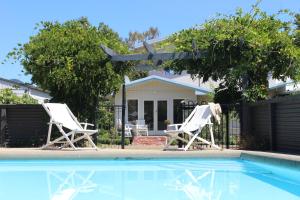 two white chairs sitting next to a swimming pool at Room for Two in Richmond