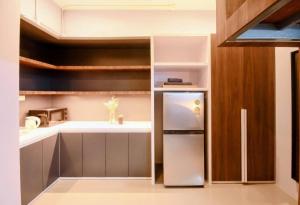 a small kitchen with a refrigerator and shelves at C2 stay Phayathai in Pom Prap