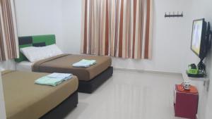a room with two beds and a television in it at DLAYARAN VILLA GUEST HOUSE in Kuala Rompin