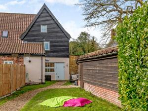 un patio trasero con un garaje y una casa en Laurel Barn en Ashwellthorpe