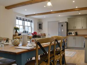 cocina y comedor con mesa de madera y sillas en Cobblers Cottage en Ripley