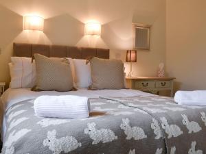 a bedroom with a large bed with a gray and white blanket at Cobblers Cottage in Ripley