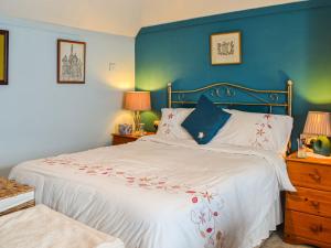 Queensland Cottage في St Margarets at Cliff: غرفة نوم بسرير كبير بجدار ازرق
