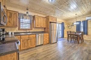 una cocina con armarios de madera y una mesa con sillas. en Quiet Pines Cabin Hocking Hills with Hot Tub and Pond, en Logan