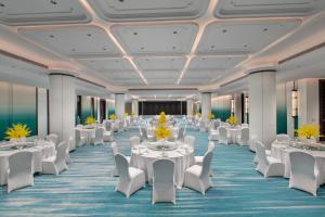 a banquet hall with white tables and white chairs at Yuehua Hotel Xiamen Seaside Hotel in Xiamen